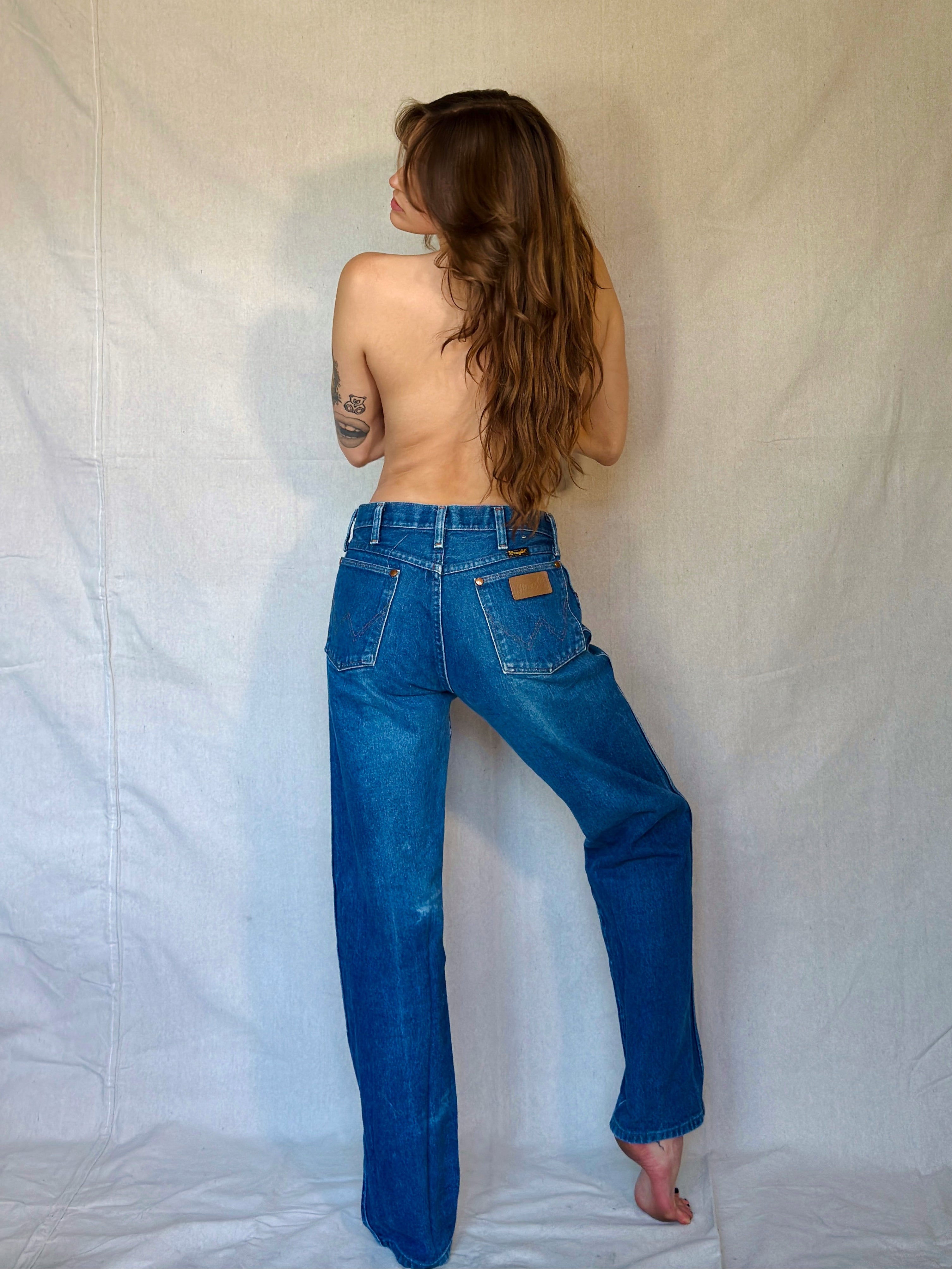Person wearing blue jeans standing against a plain white background