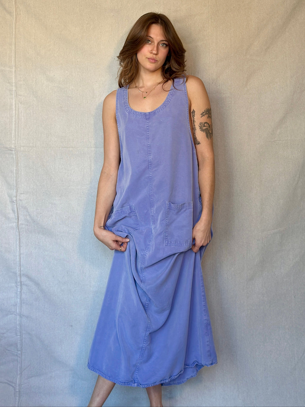 Woman wearing a purple sleeveless dress against a plain background