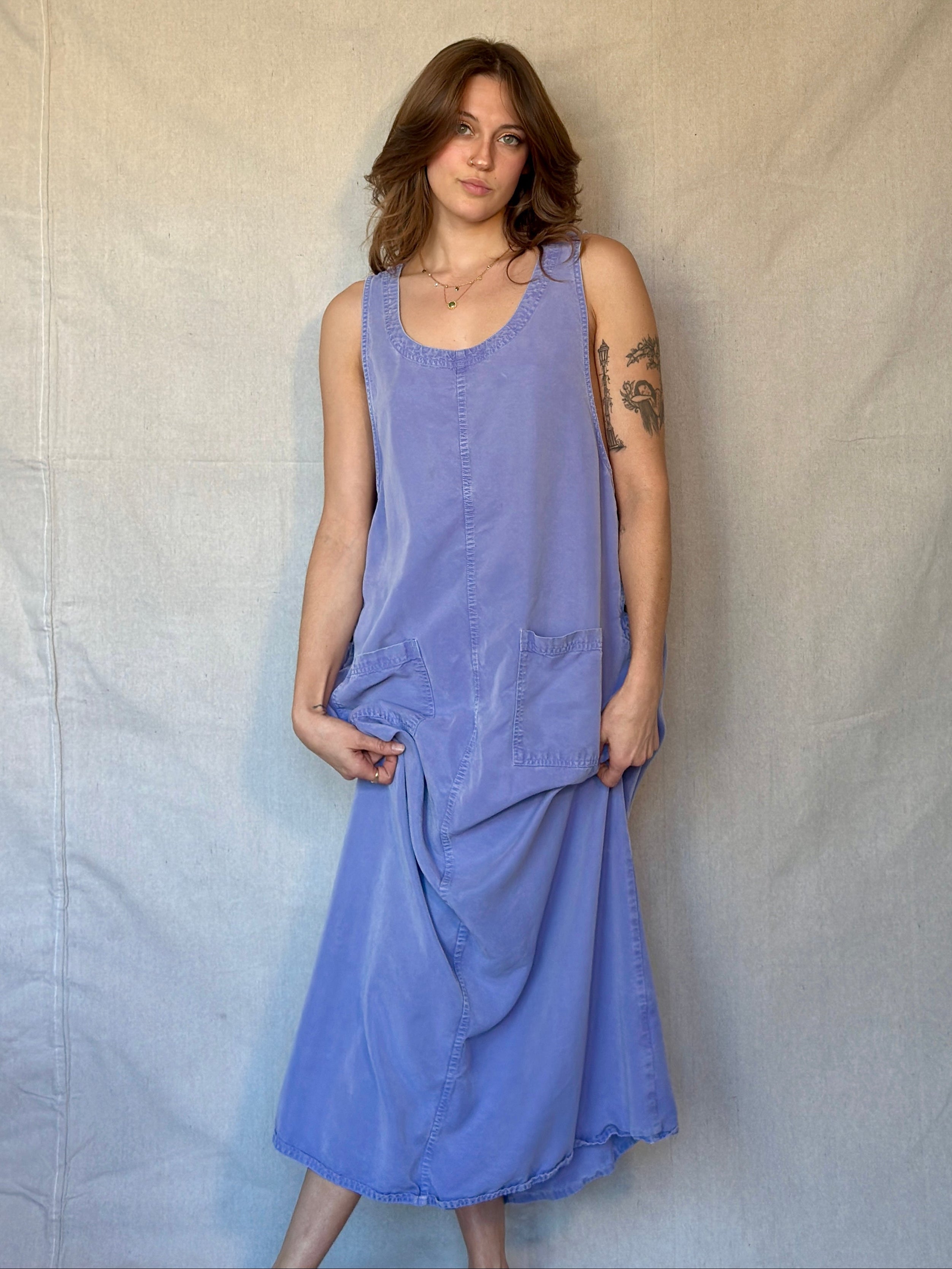 Woman wearing a purple sleeveless dress against a plain background