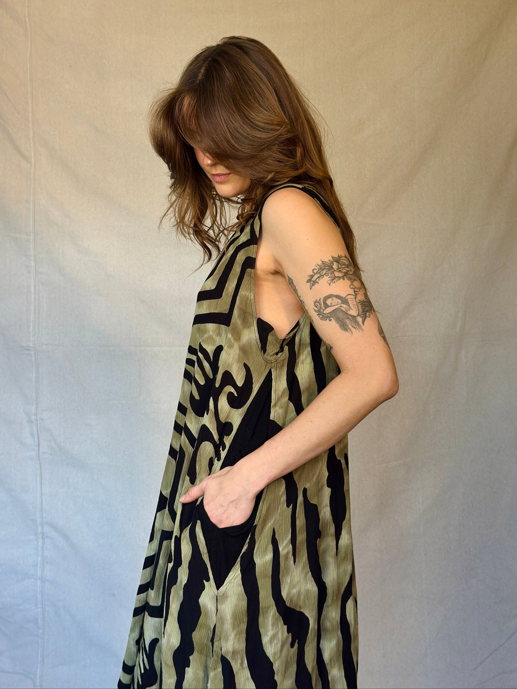 Person wearing a sleeveless patterned dress against a plain background