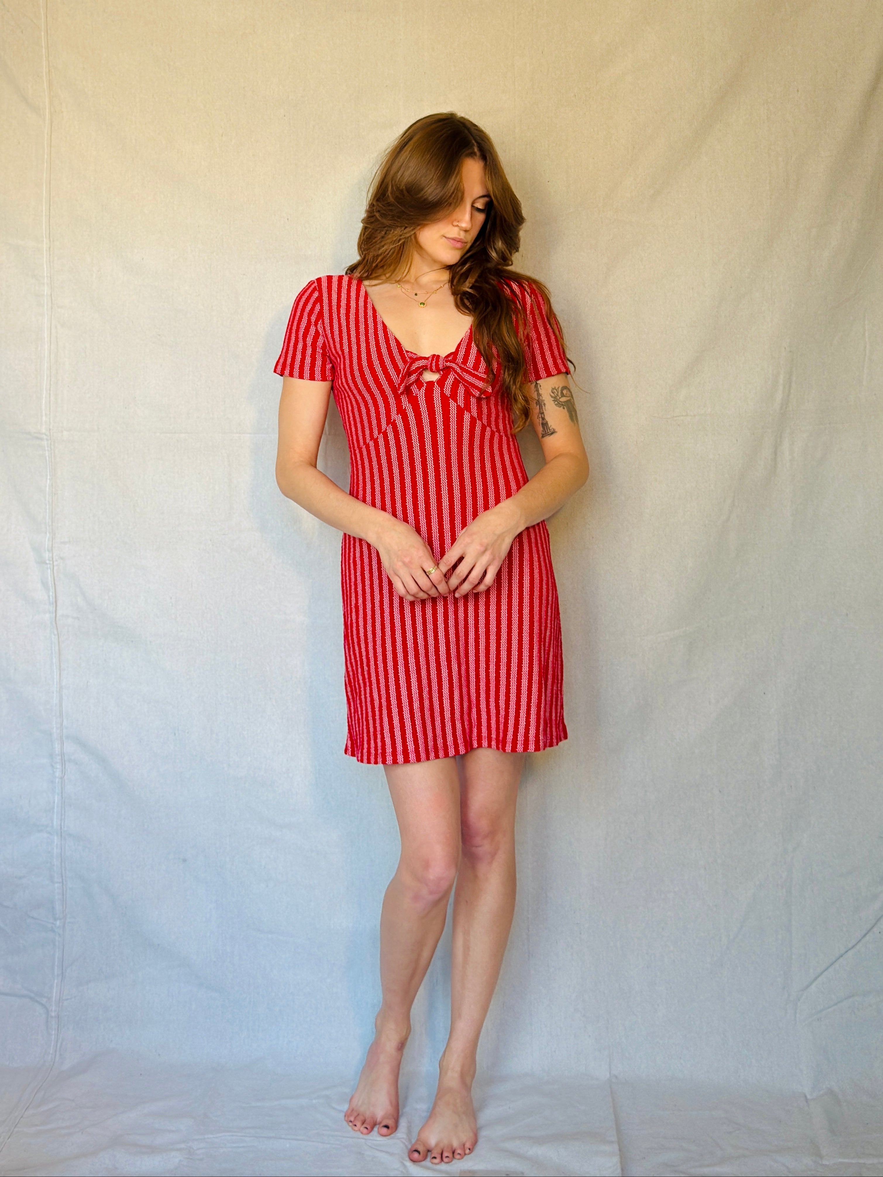 Woman wearing a red and white striped dress against a plain background