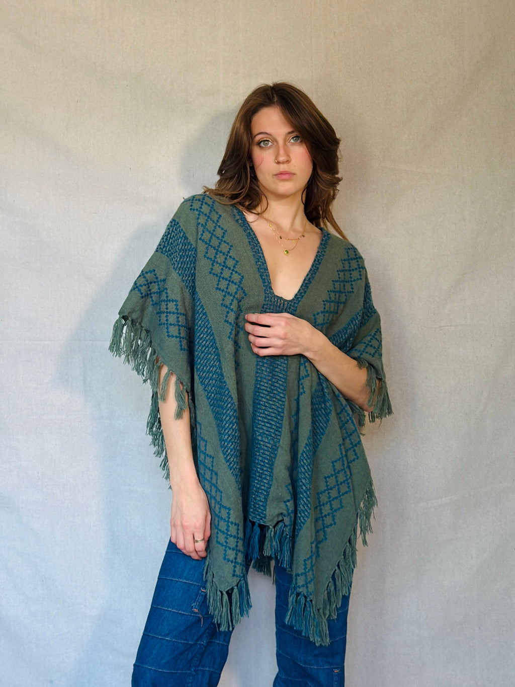Woman wearing a green patterned shawl over a plain background