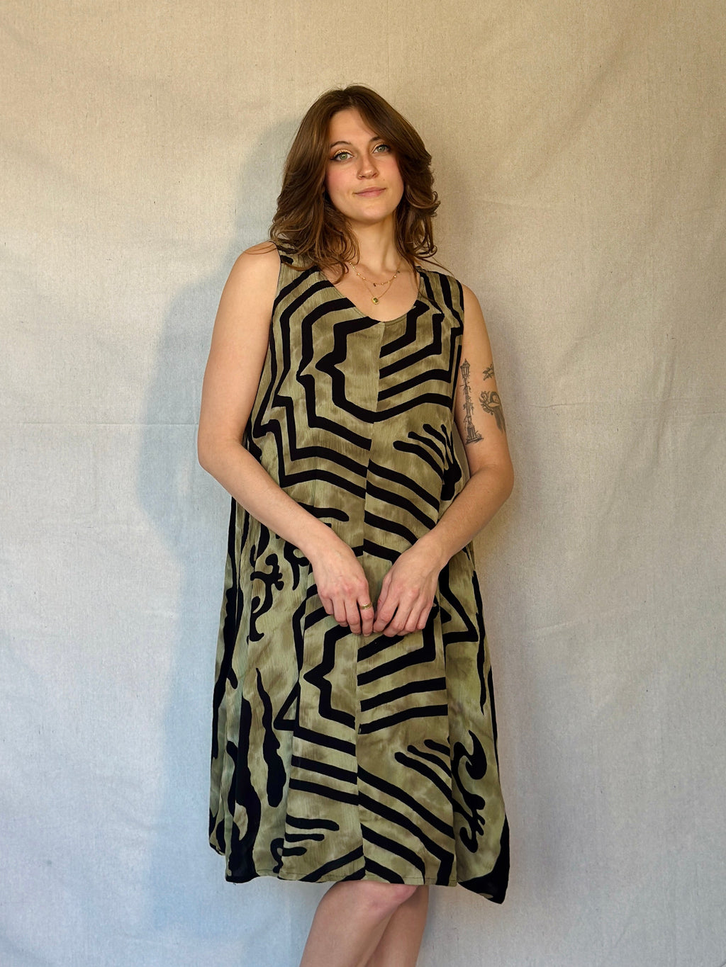 Woman wearing a sleeveless dress with geometric pattern against a plain background