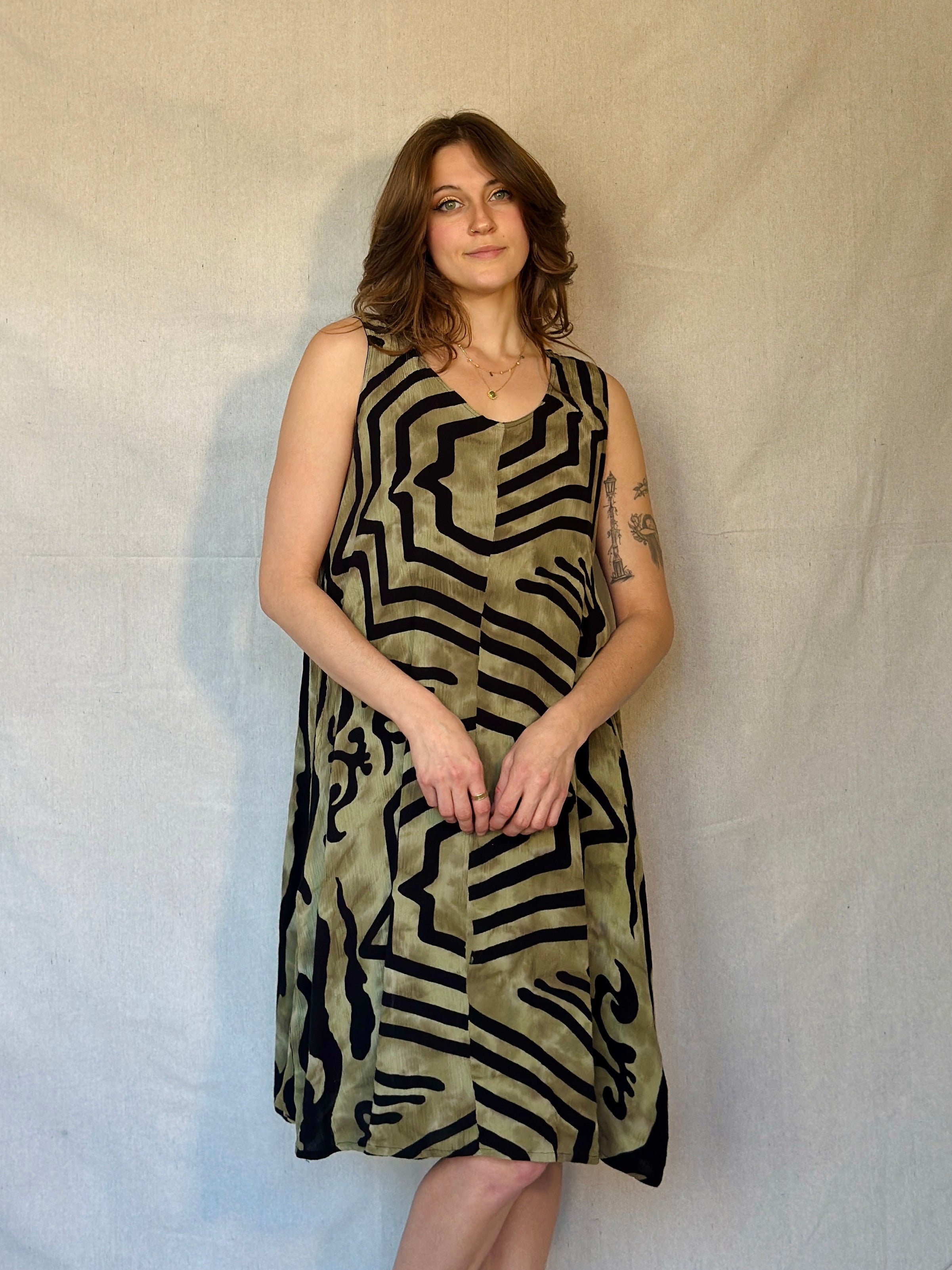 Woman wearing a sleeveless dress with geometric pattern against a plain background