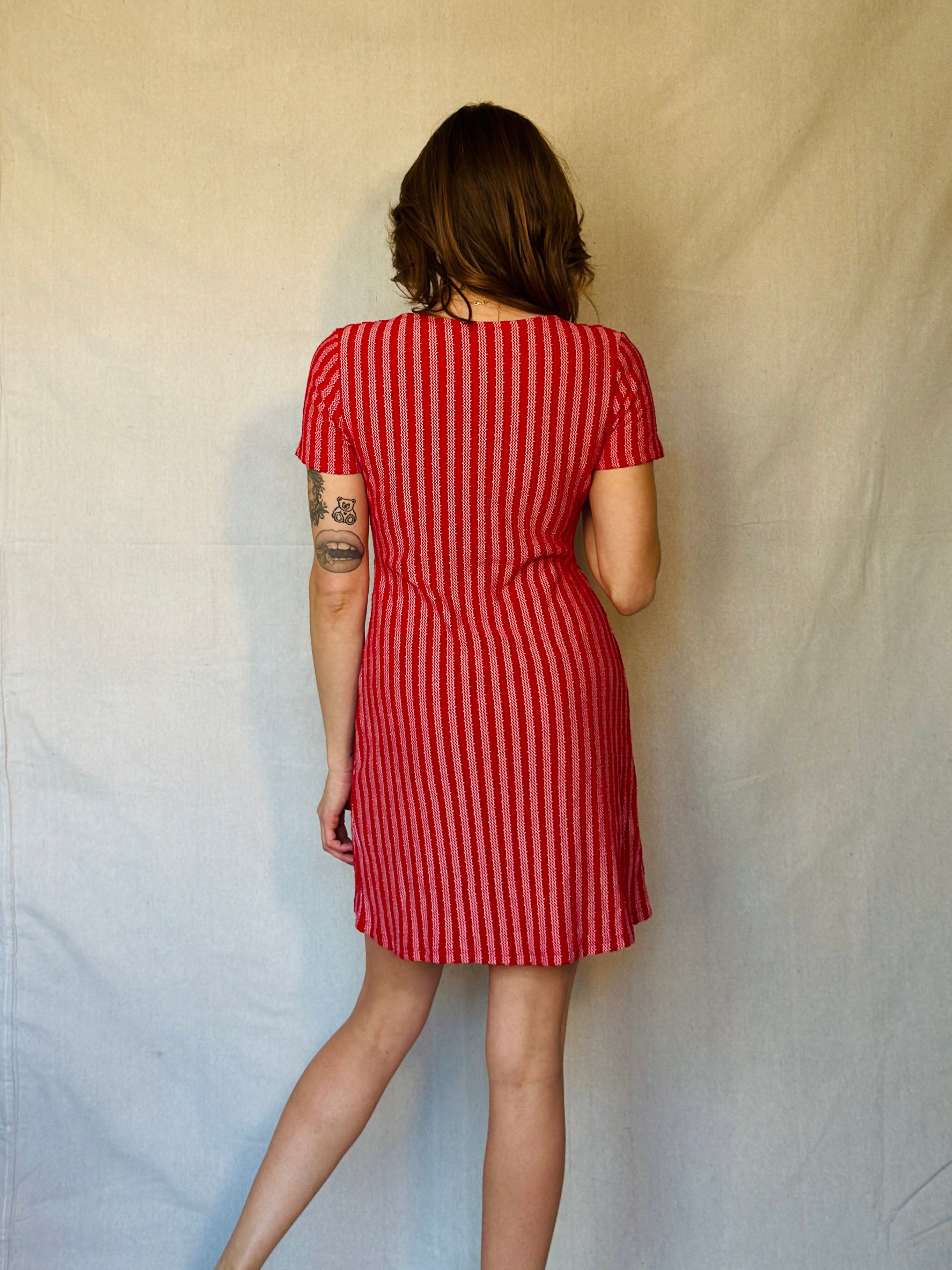 Person wearing a red and white striped dress against a plain background