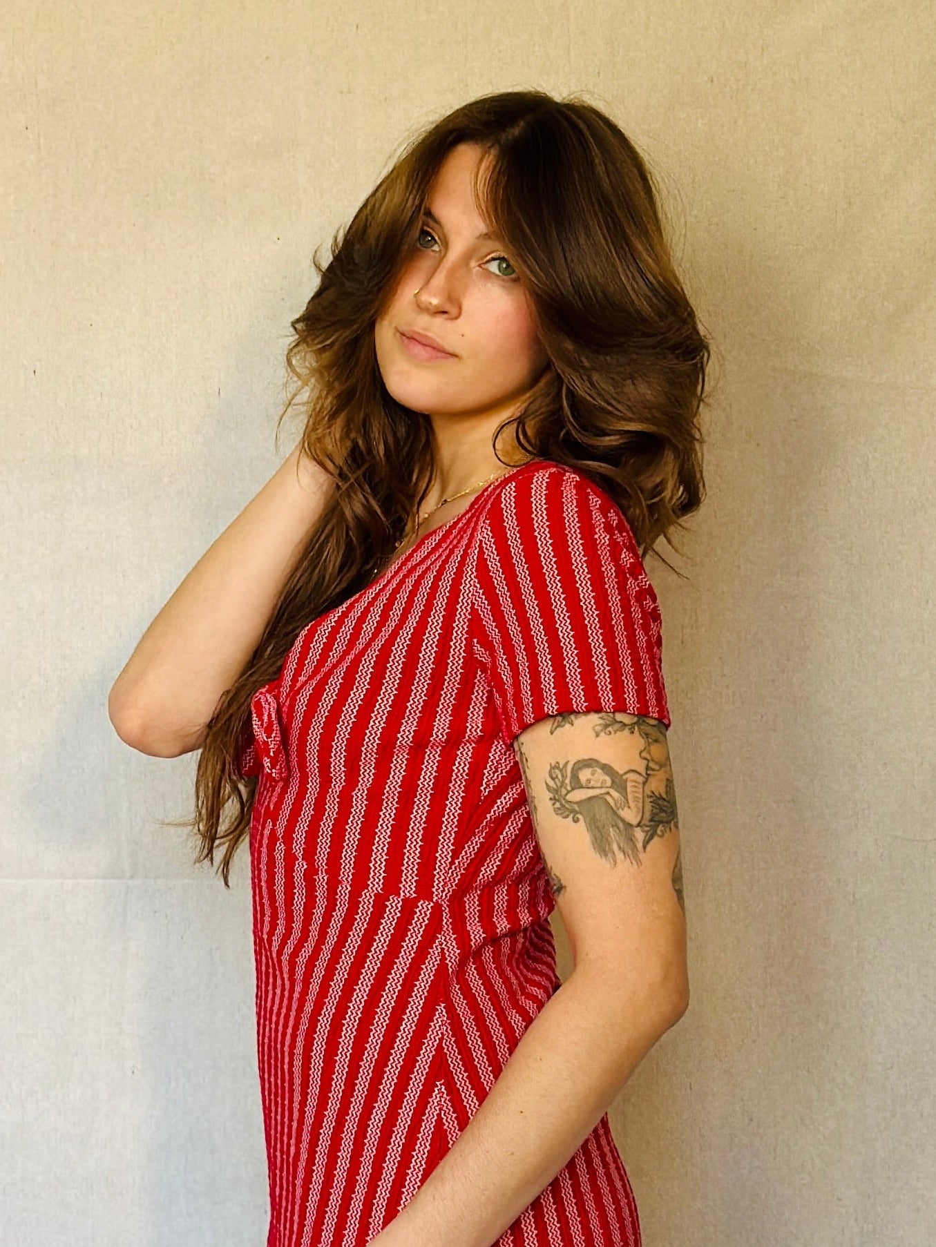 Woman wearing a red and white striped dress against a plain background