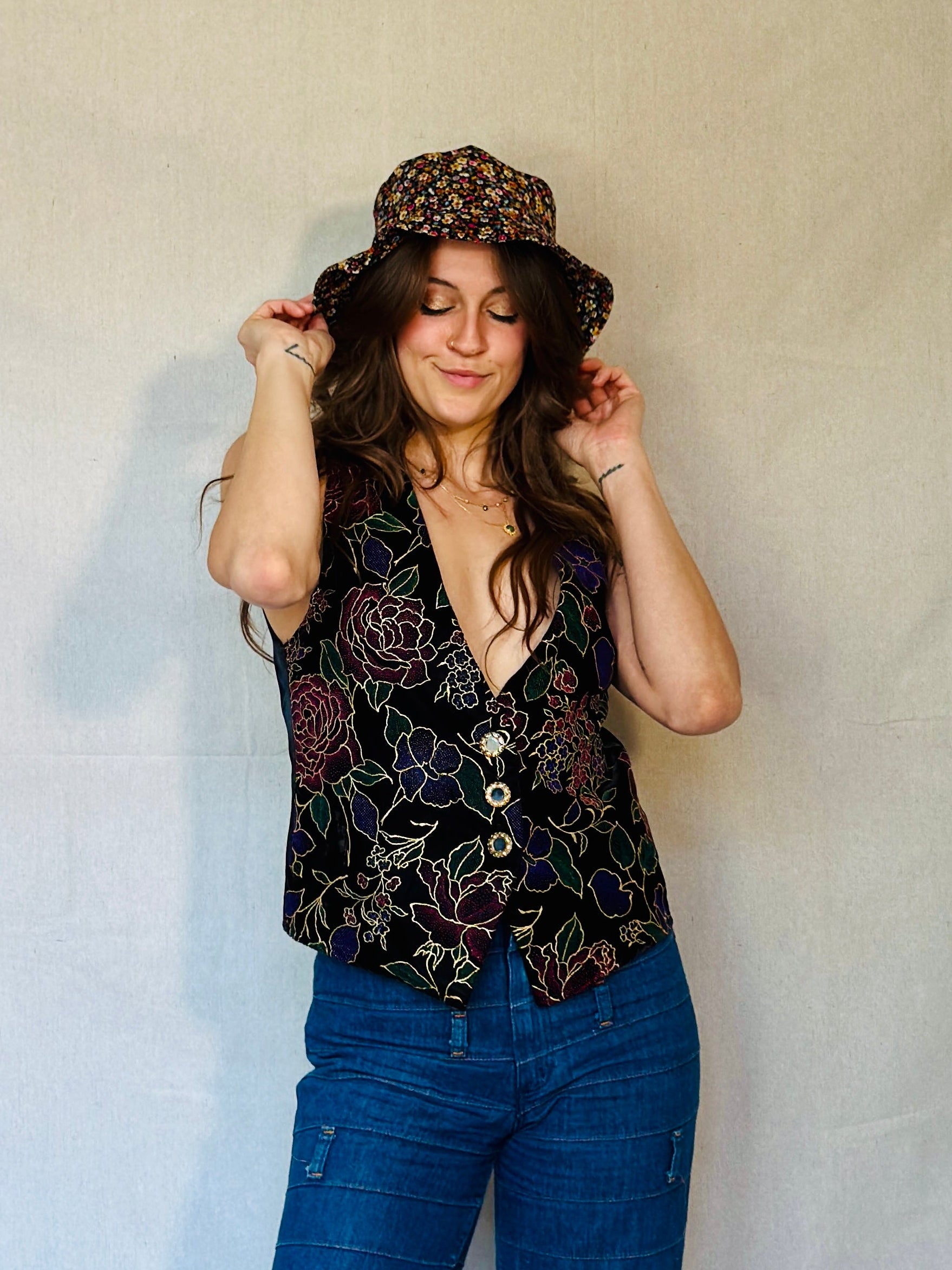 Person wearing a patterned top and blue jeans against a plain background