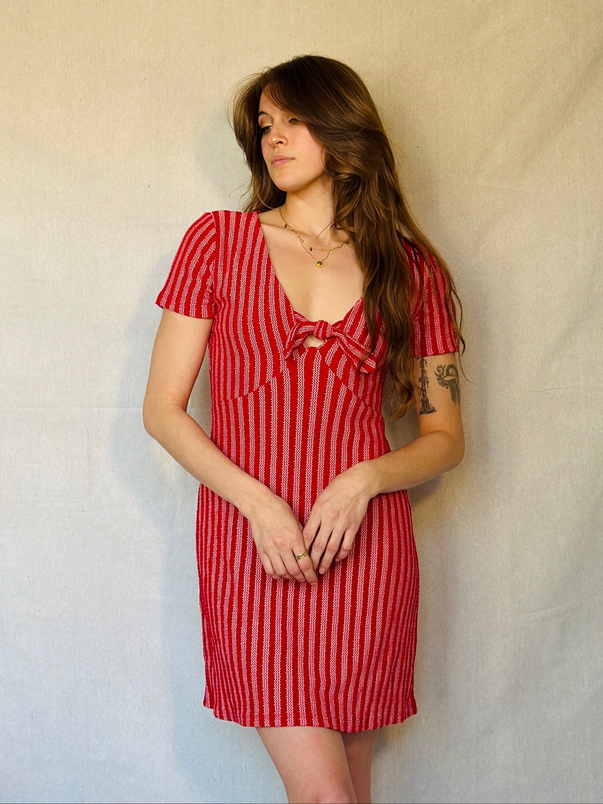 Woman wearing a red and white striped dress against a plain background