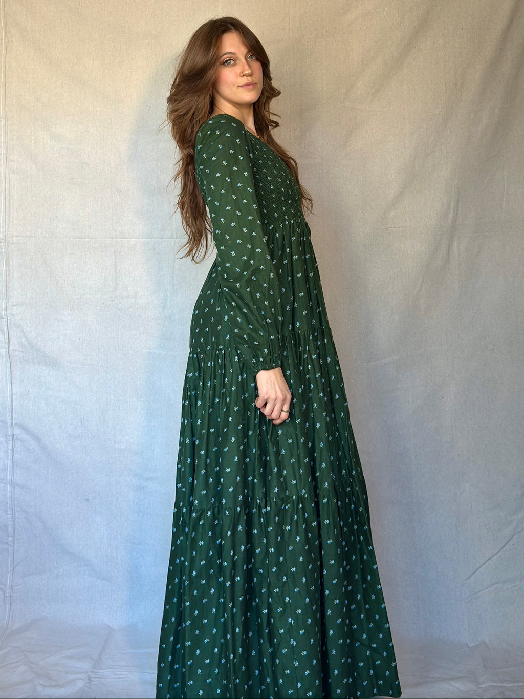 Woman wearing a green dress with blue and white micro floral pattern against a plain background